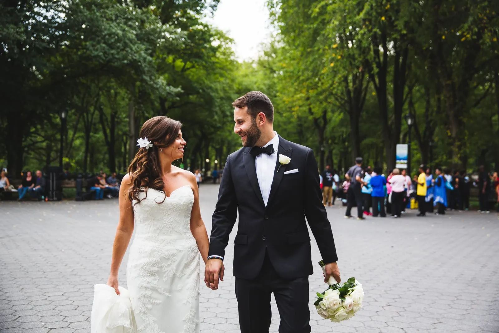 Newlyweds walking hand in hand on the Mall under the elms