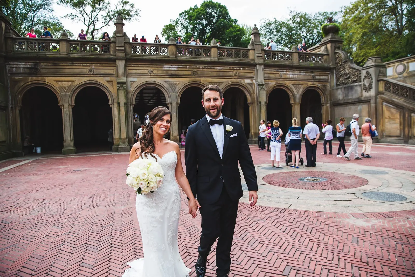 Bride and groom walking across Bethesda Terrace