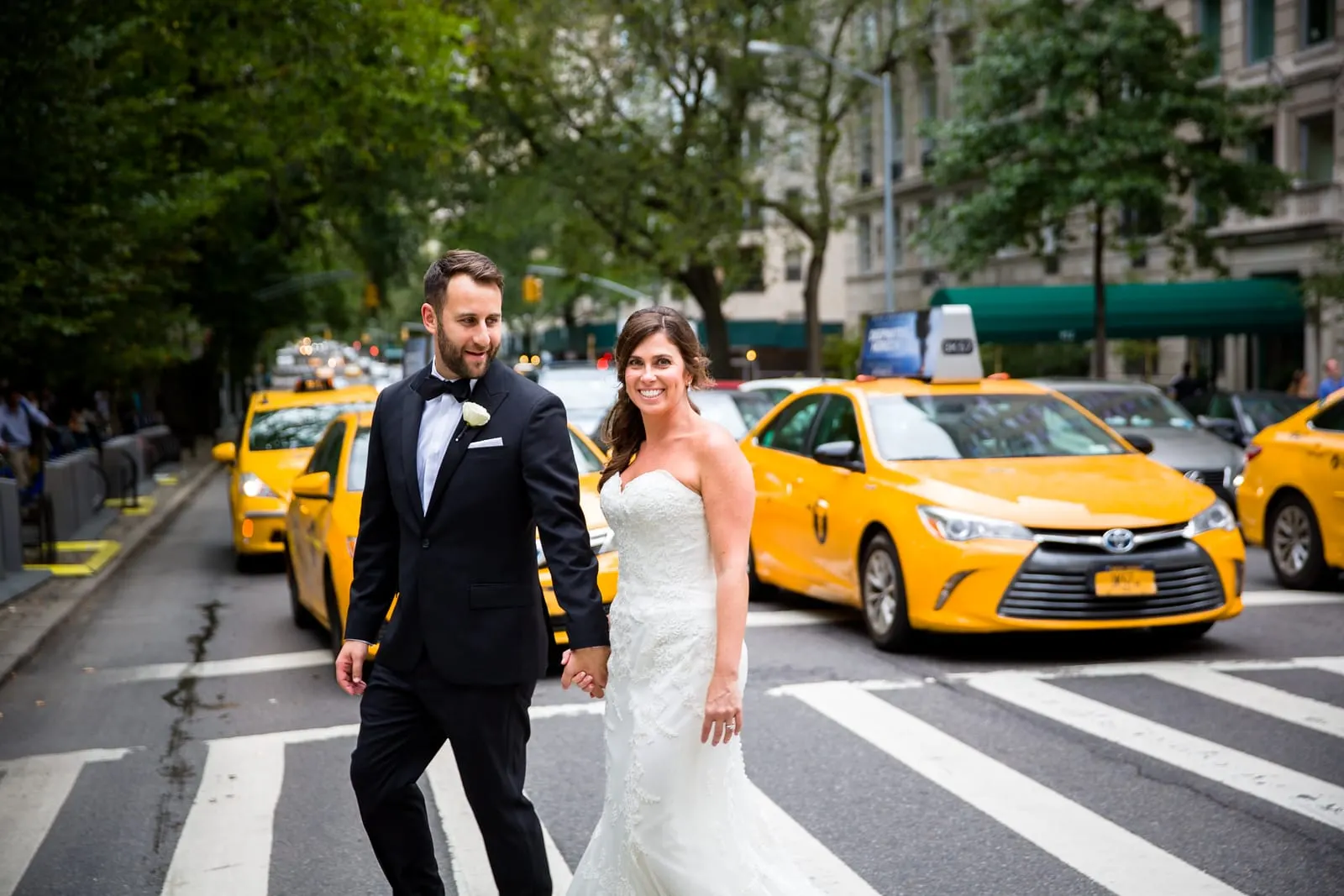 Bride and groom crossing Central Park South with yellow taxis behind them