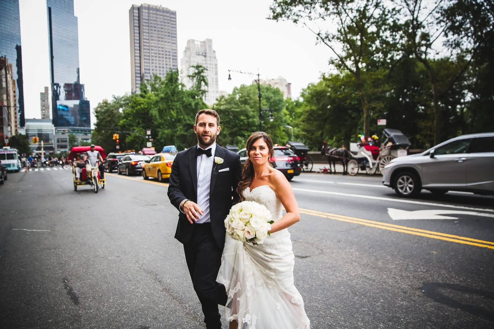 Bride and groom on Central Park South with Columbus Circle behind them