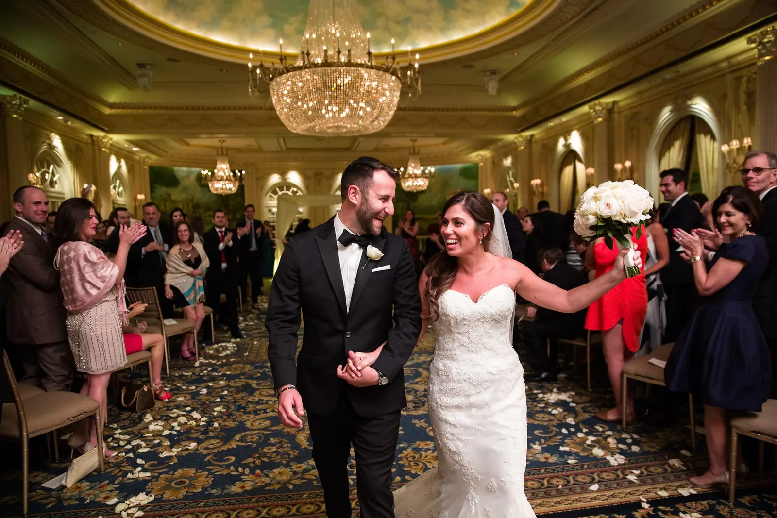 Newlyweds walking back down the aisle as guests cheer