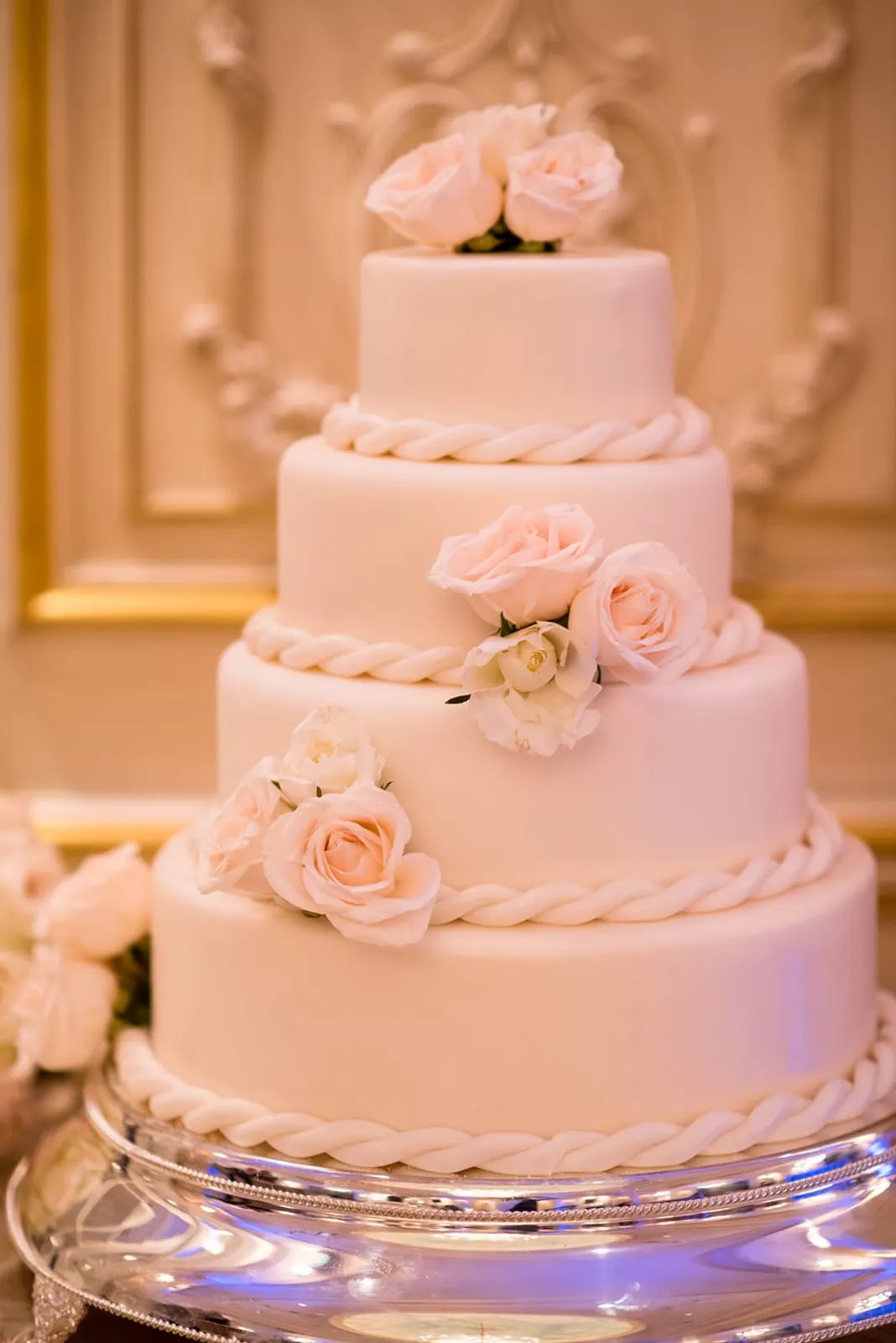Four-tier white wedding cake with roses