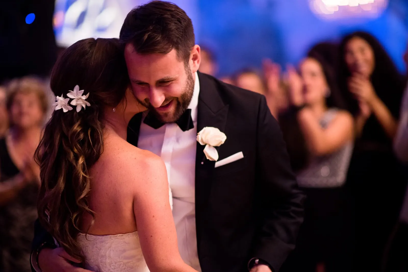 Groom resting his head against the bride on the dance floor