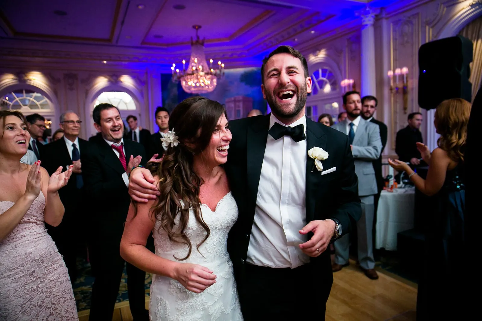Groom laughing with his arm around the bride during the hora