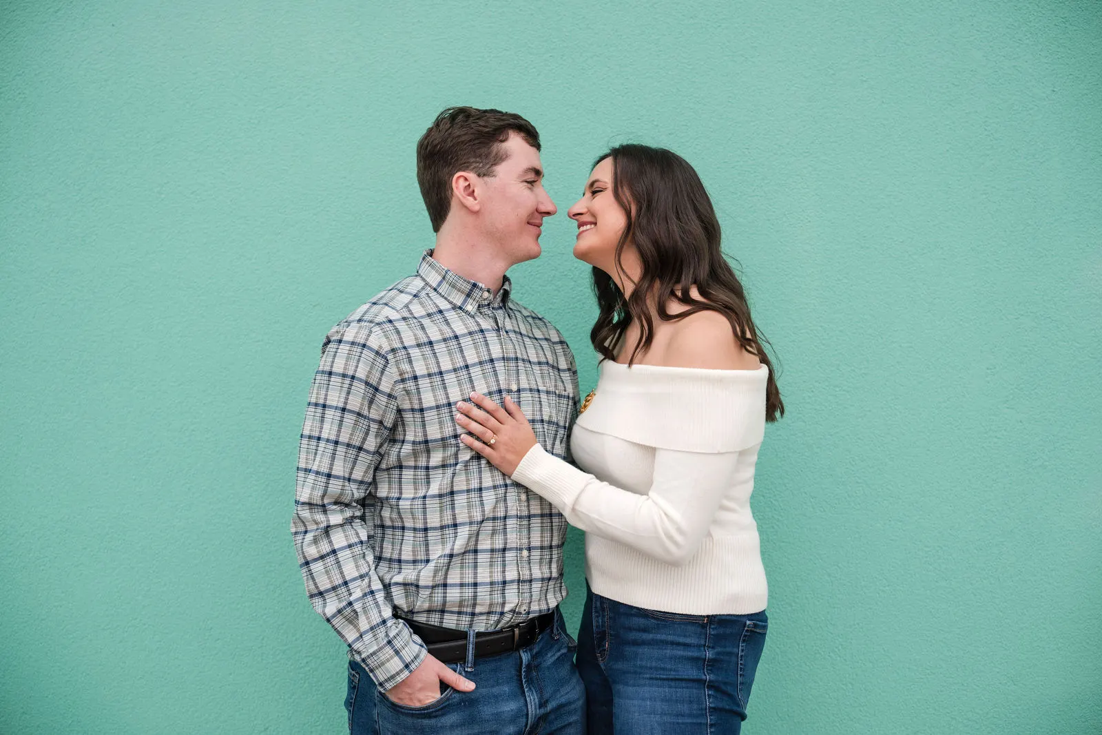 Engaged couple touching noses in front of a bright turquoise wall in Asbury Park, New Jersey