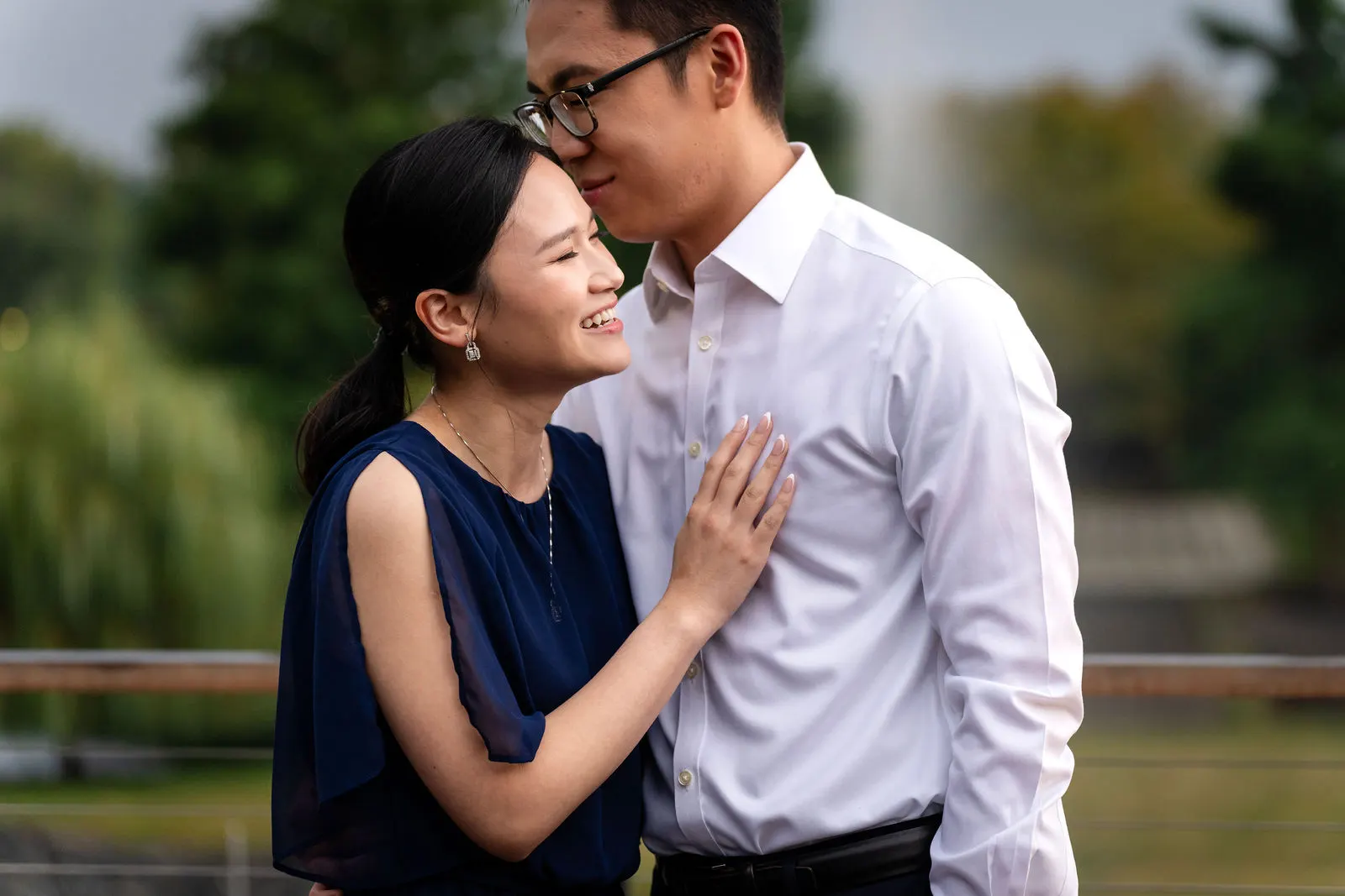 Bride-to-be smiling with her hand on her fiance's chest during a rainy engagement session at Bell Labs in Holmdel, NJ