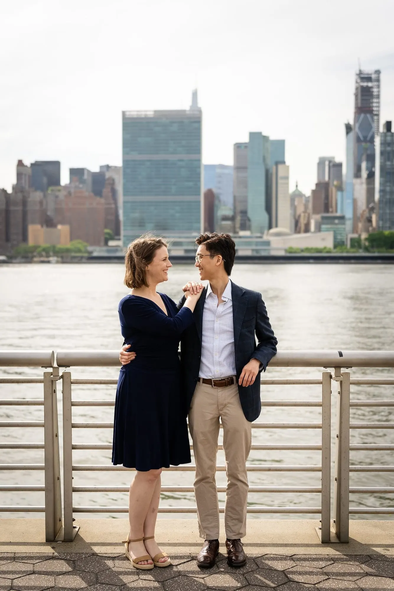 Couple at the railing with the United Nations and Midtown skyline behind them