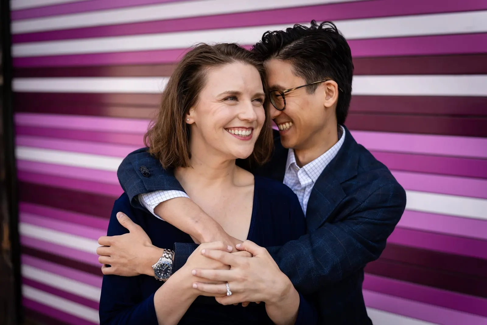 Couple laughing together against a purple striped wall