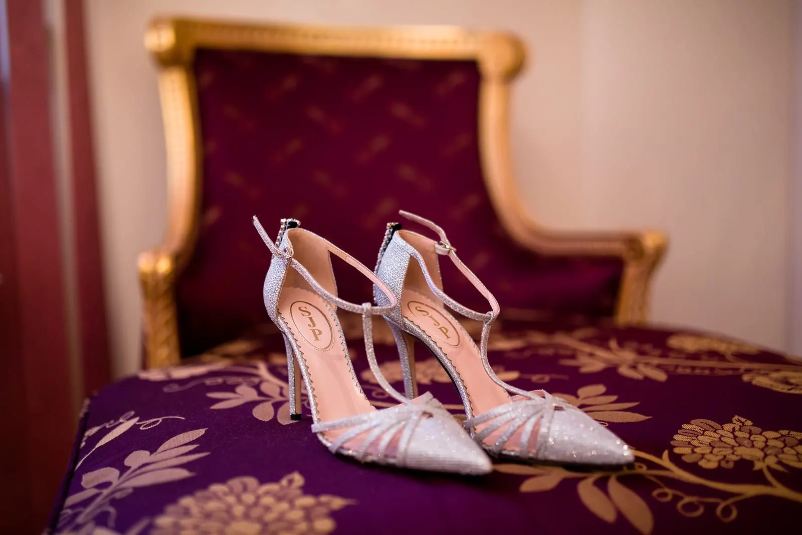 Sparkling T-strap bridal heels on a gold and burgundy chair