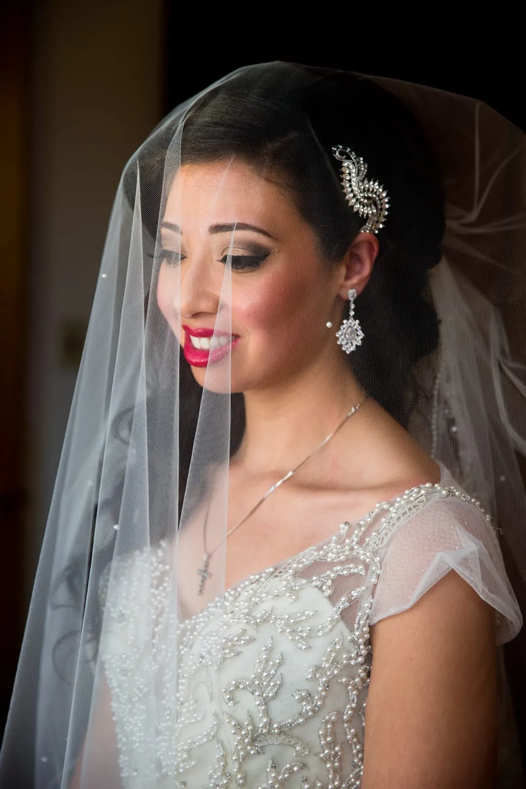 Bride under her lace-trimmed veil by the window