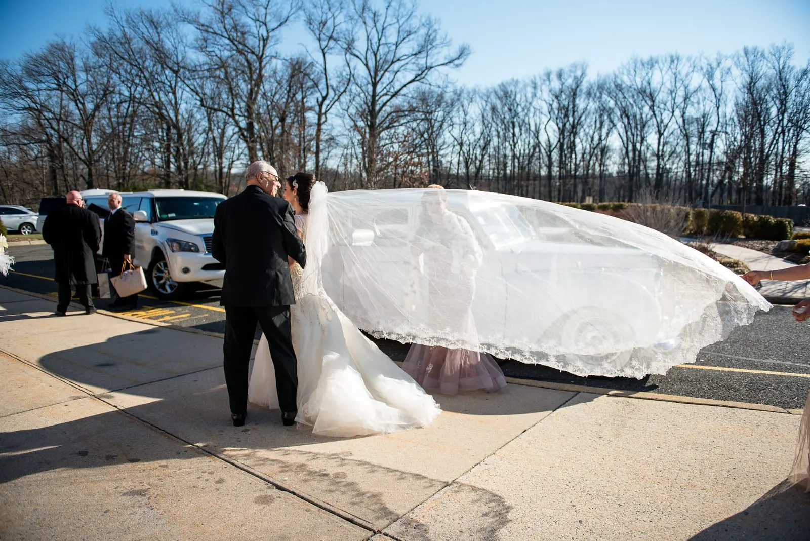 Bride's long veil catching the wind outside the cathedral