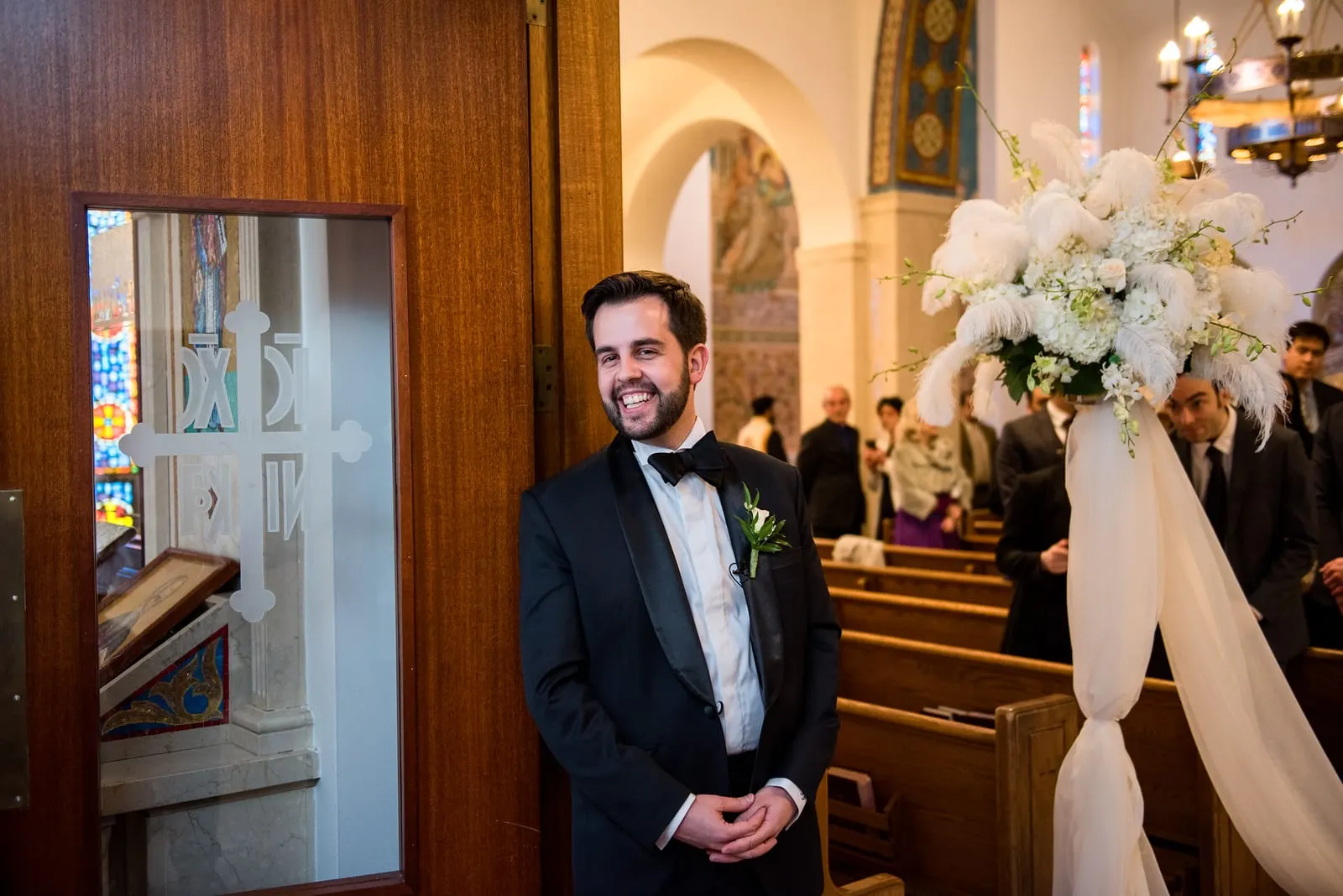 Groom smiling as he waits at the front of the cathedral