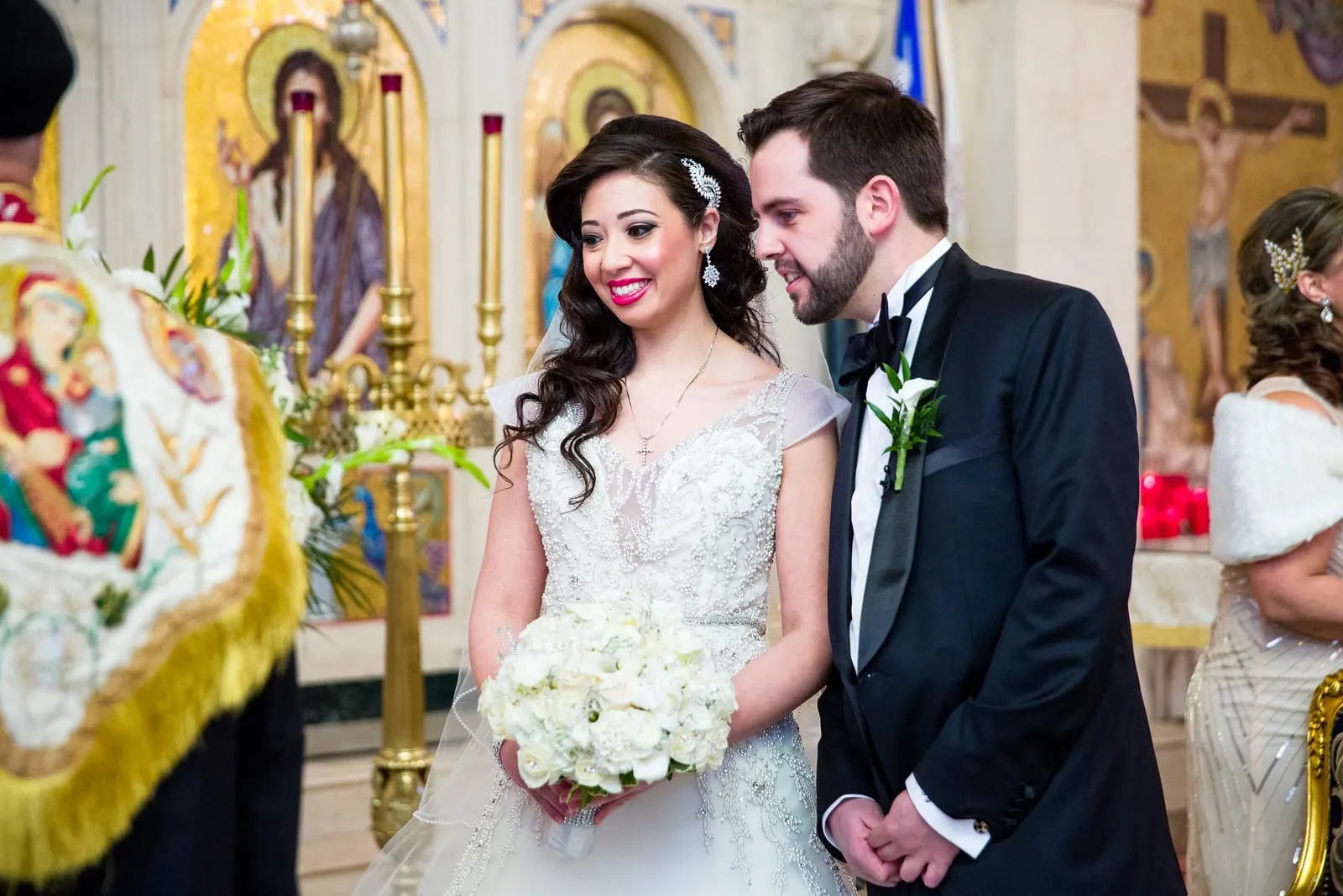 Bride and groom smiling at each other before the iconostasis