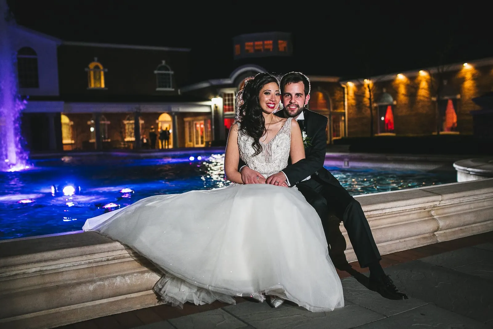 Bride and groom by the lit fountain at night outside Rockleigh Country Club