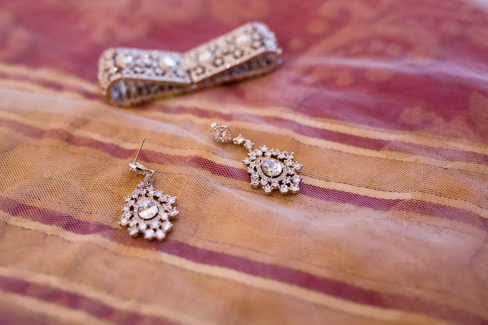 Crystal bracelet and chandelier earrings on a striped silk throw