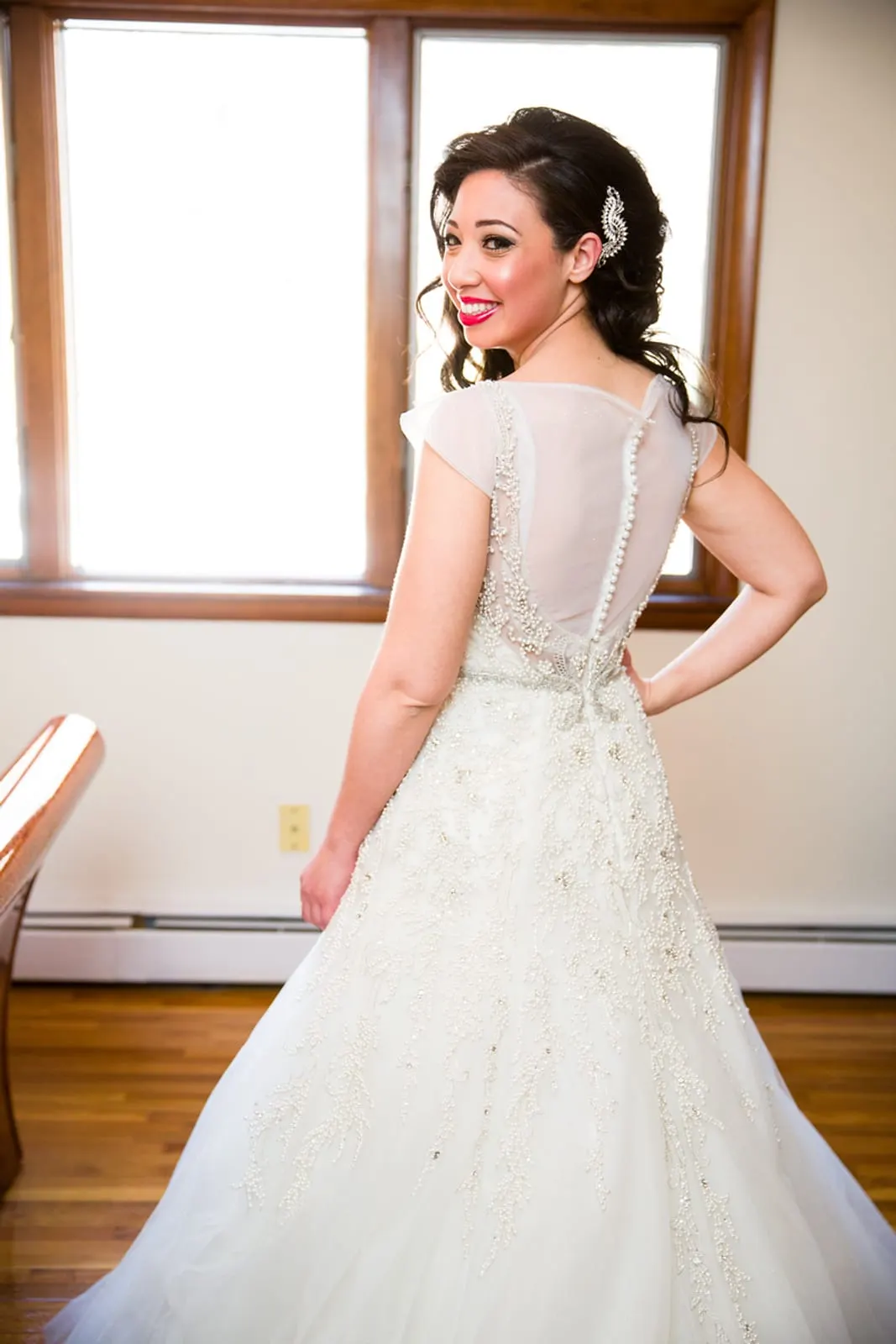 Back of the bride's gown as she looks over her shoulder by the window