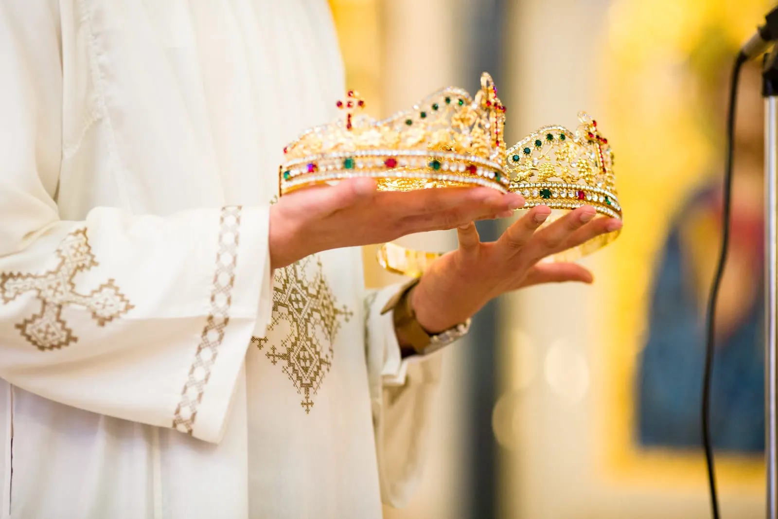 Jeweled wedding crowns held by an altar server