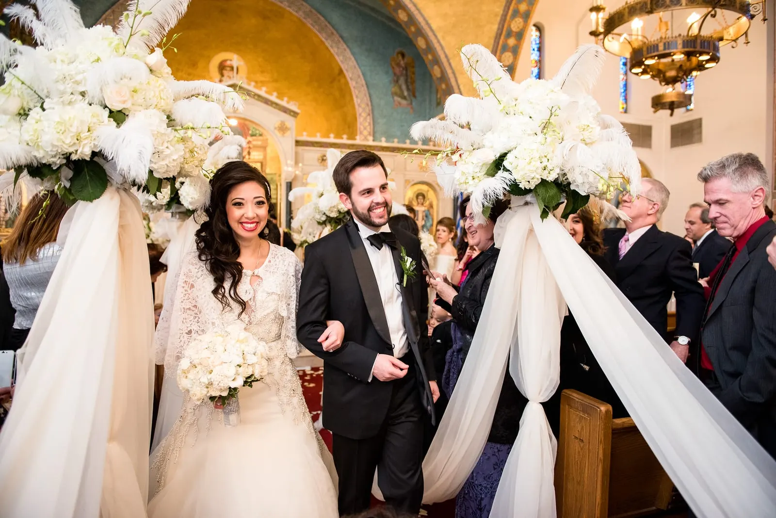 Bride and groom walking back down the aisle past the white floral pillars