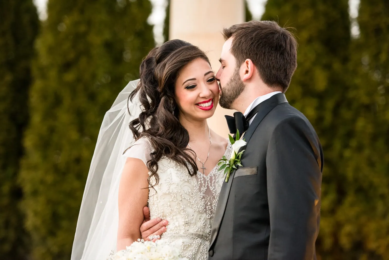 Groom kissing the bride's cheek as she laughs