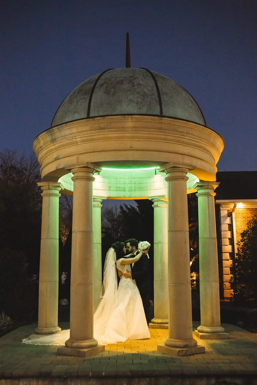 Bride and groom under the illuminated rotunda at dusk