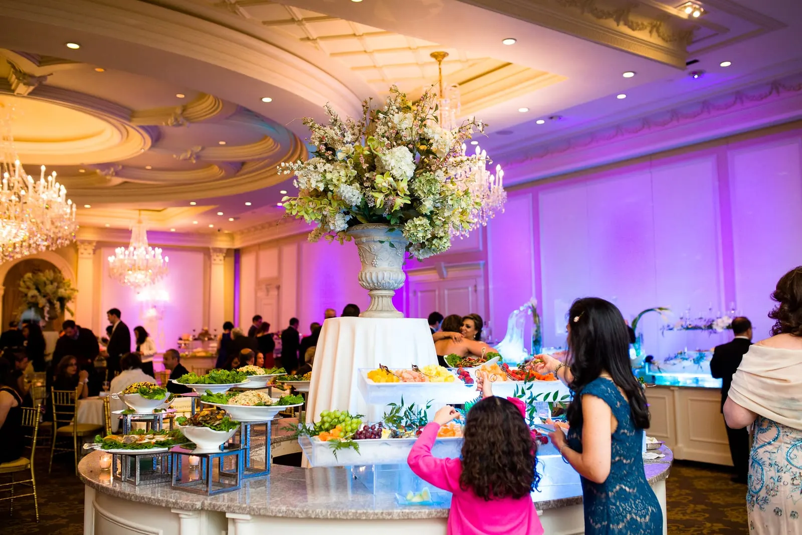 Cocktail hour food station under a tall floral centerpiece