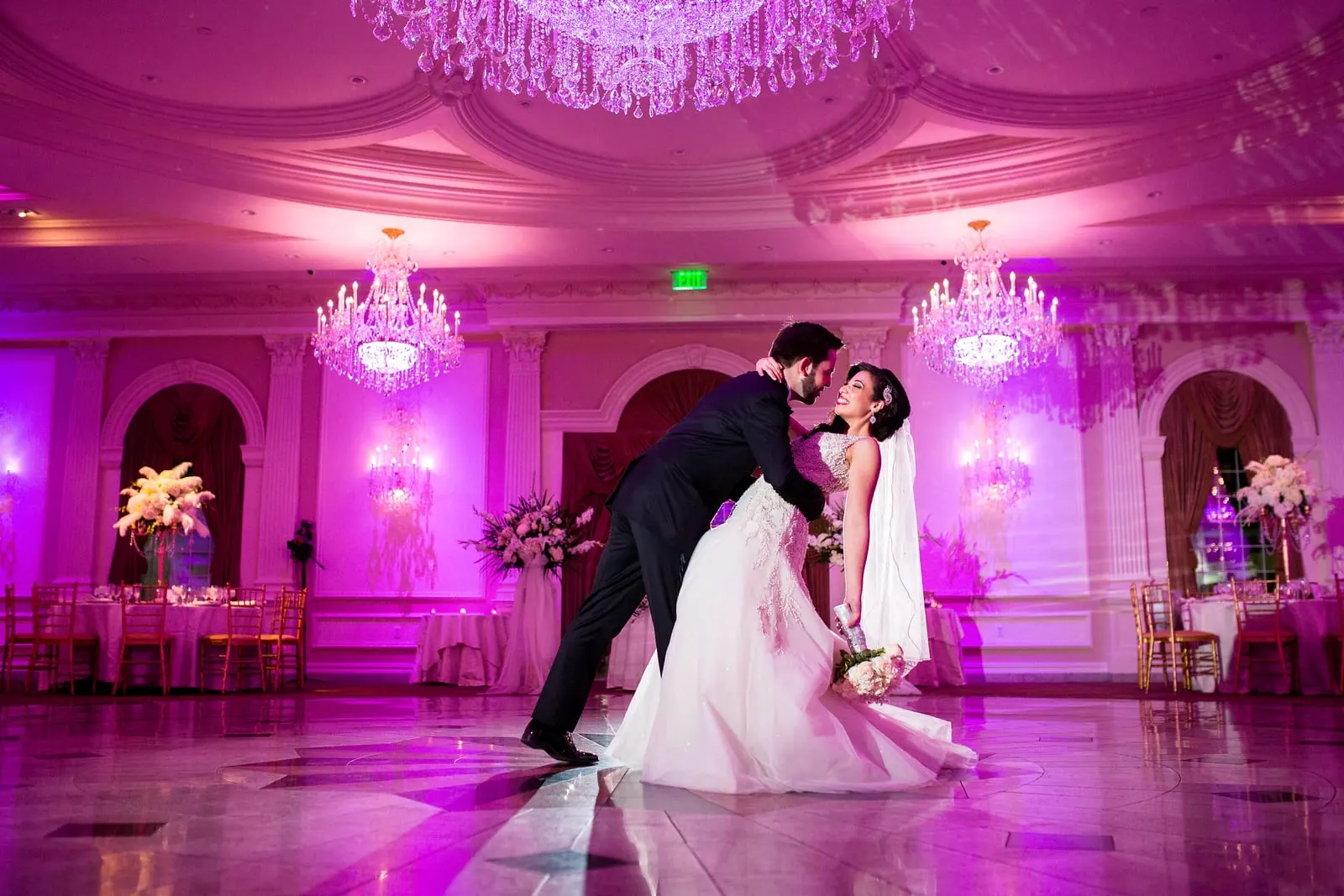 Groom dipping the bride on the empty ballroom dance floor