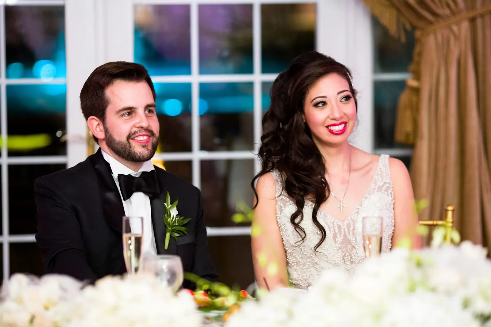 Bride and groom laughing at the sweetheart table during the toasts
