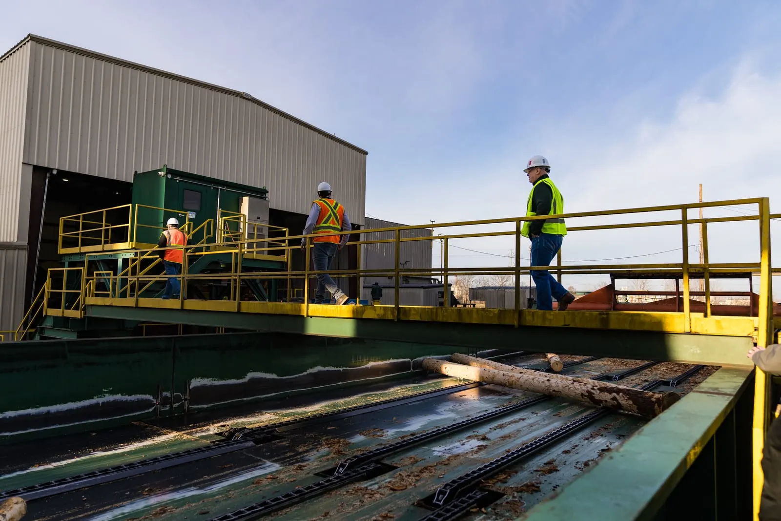 Visitors on a catwalk above the log deck at the sawmill