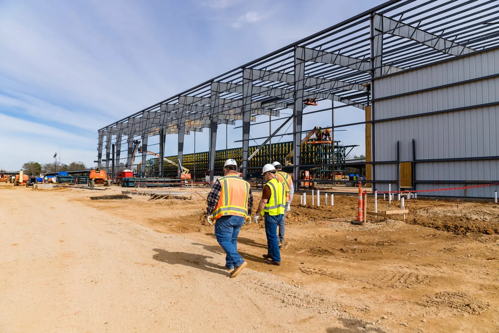 Wide view of the new facility's steel frame with visitors walking