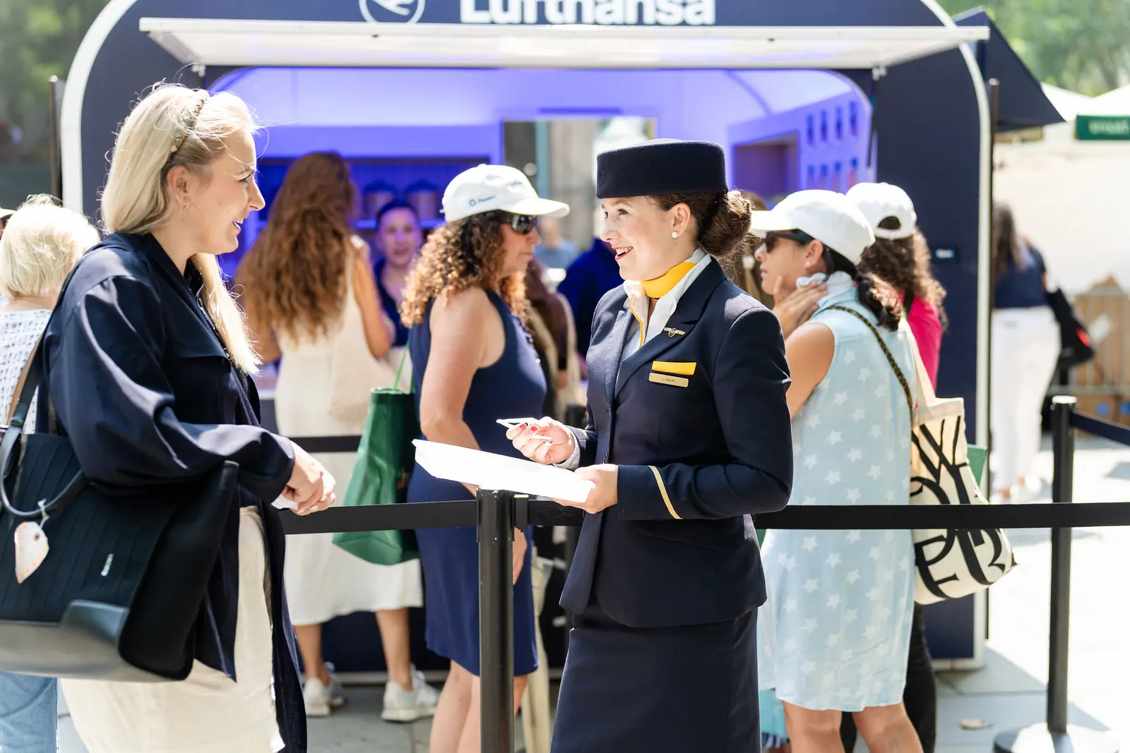 Lufthansa crew welcoming guests waiting in line at the booth