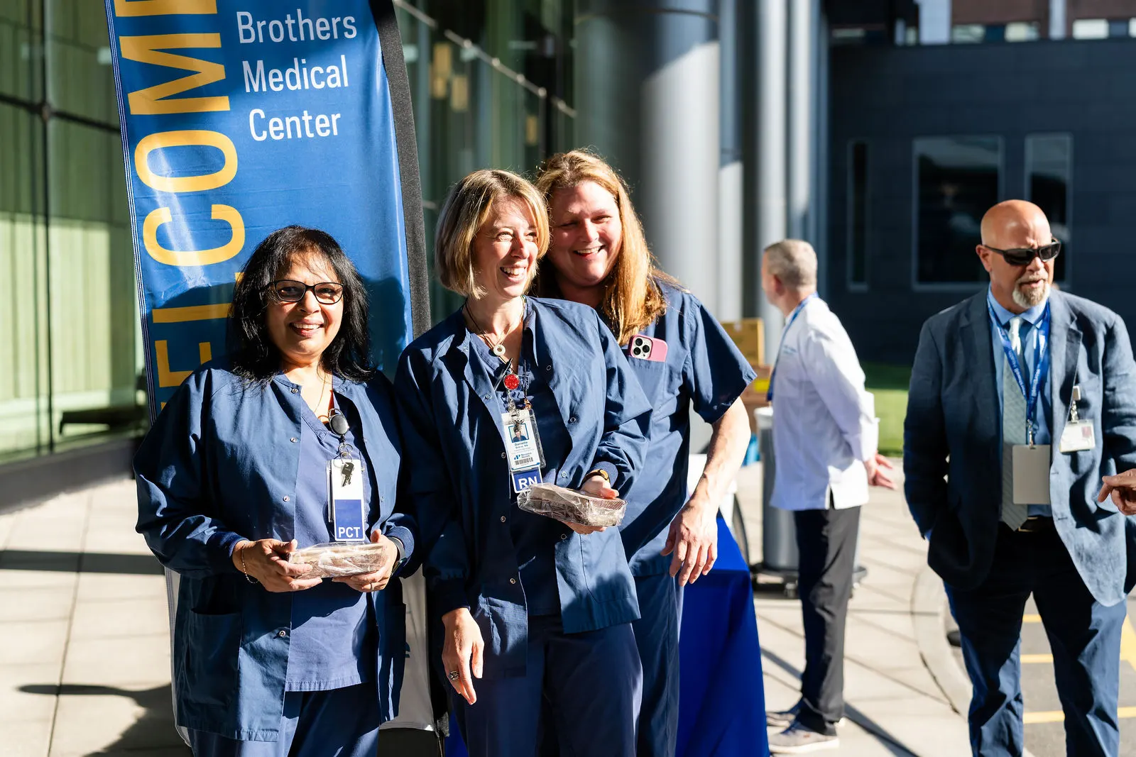 Smiling Vassar Brothers Medical Center staff by the Welcome banner