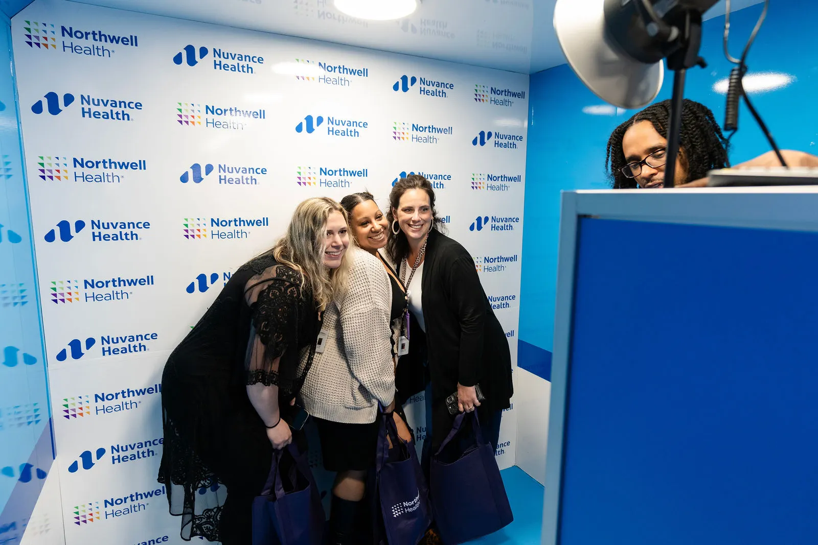 Smiling staff posing in a photo booth with a Northwell Health and Nuvance Health logo backdrop at The Summit