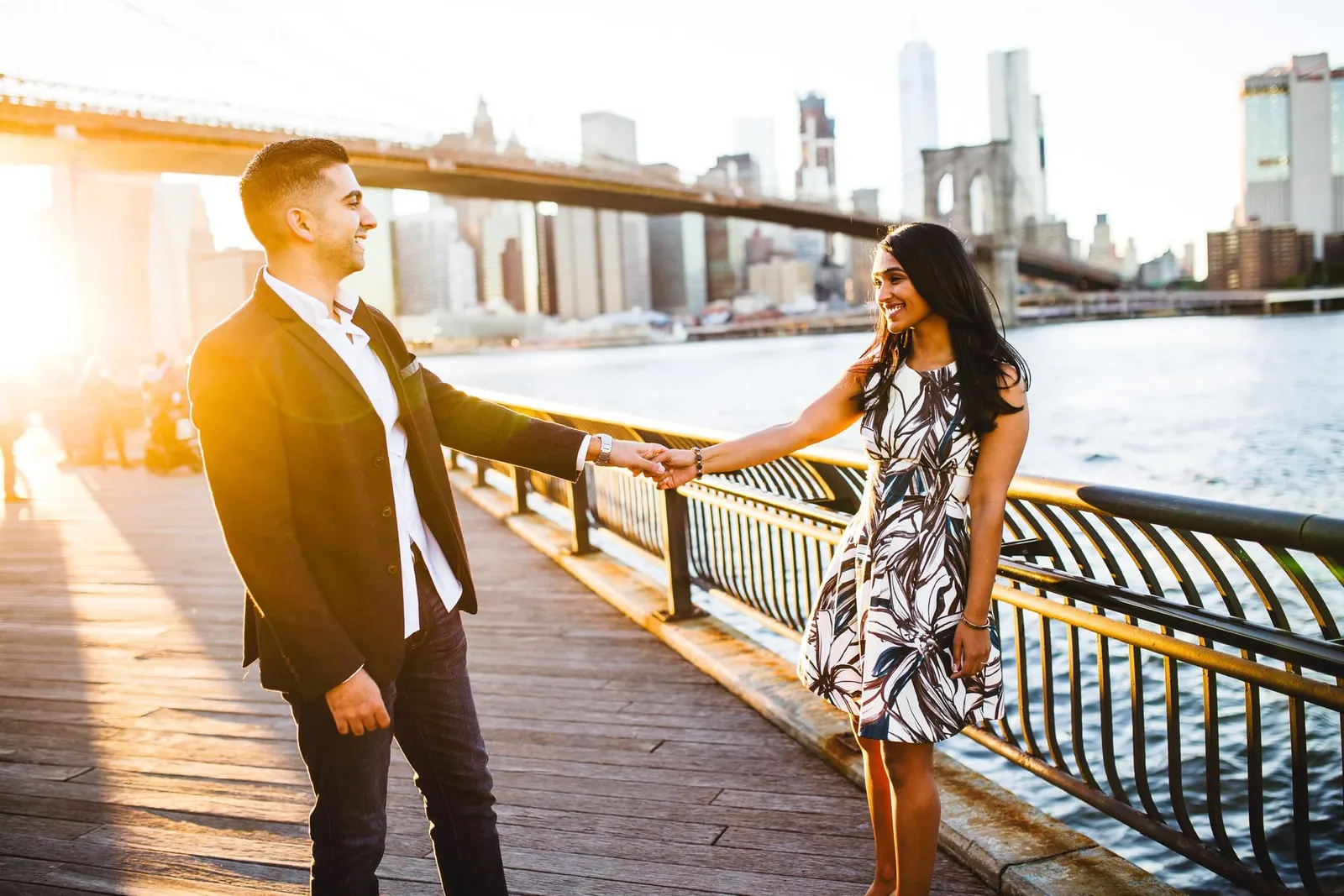 Engaged couple on the Brooklyn waterfront in DUMBO at golden hour with the Manhattan skyline behind them