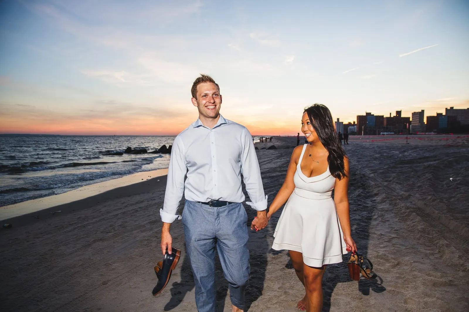 Couple walking barefoot on the beach at Coney Island at sunset