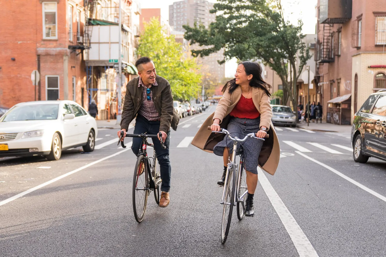 Couple riding bicycles together down a street in Williamsburg, Brooklyn during their engagement session