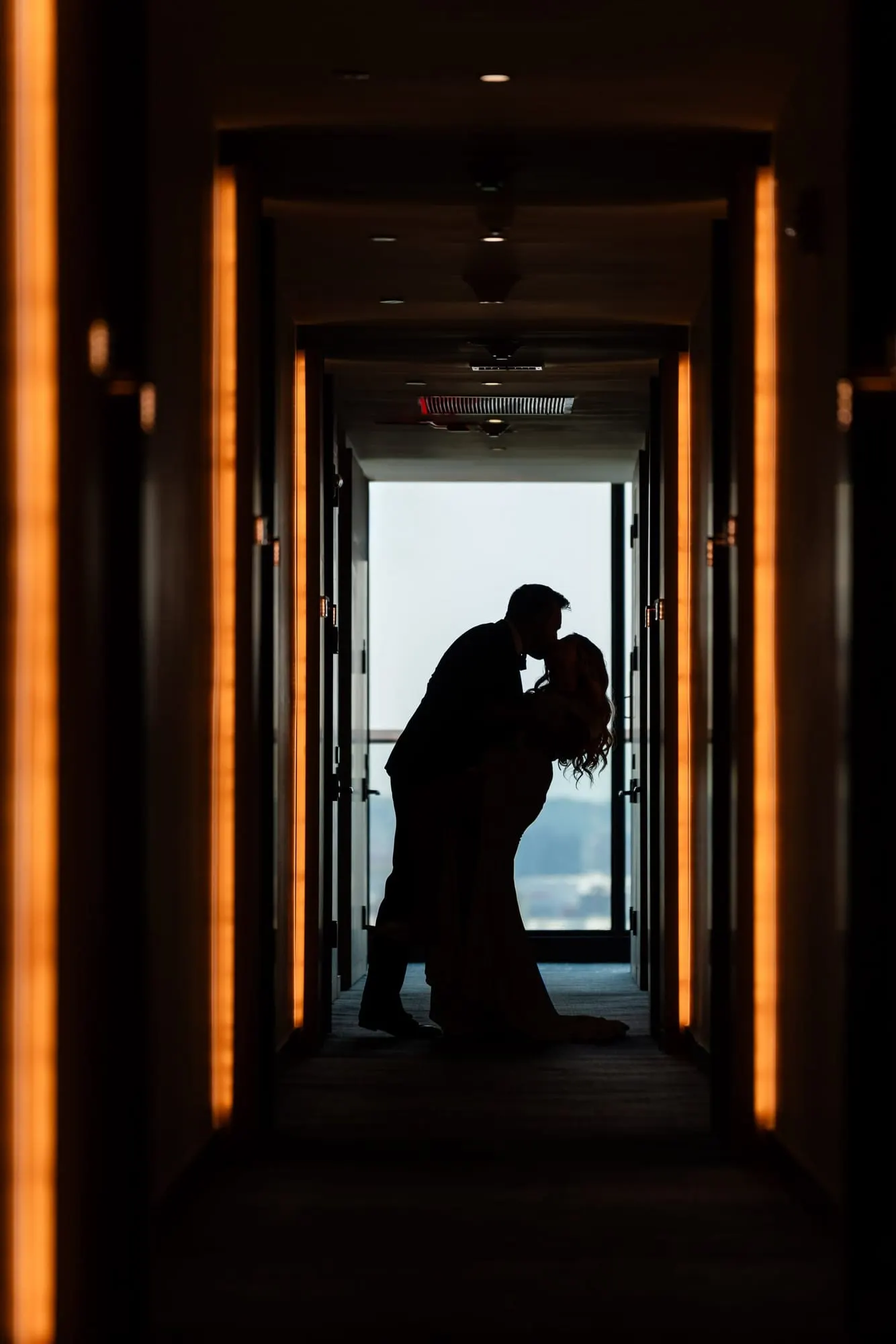 Silhouette of a couple embracing at the end of a long hallway during their first look