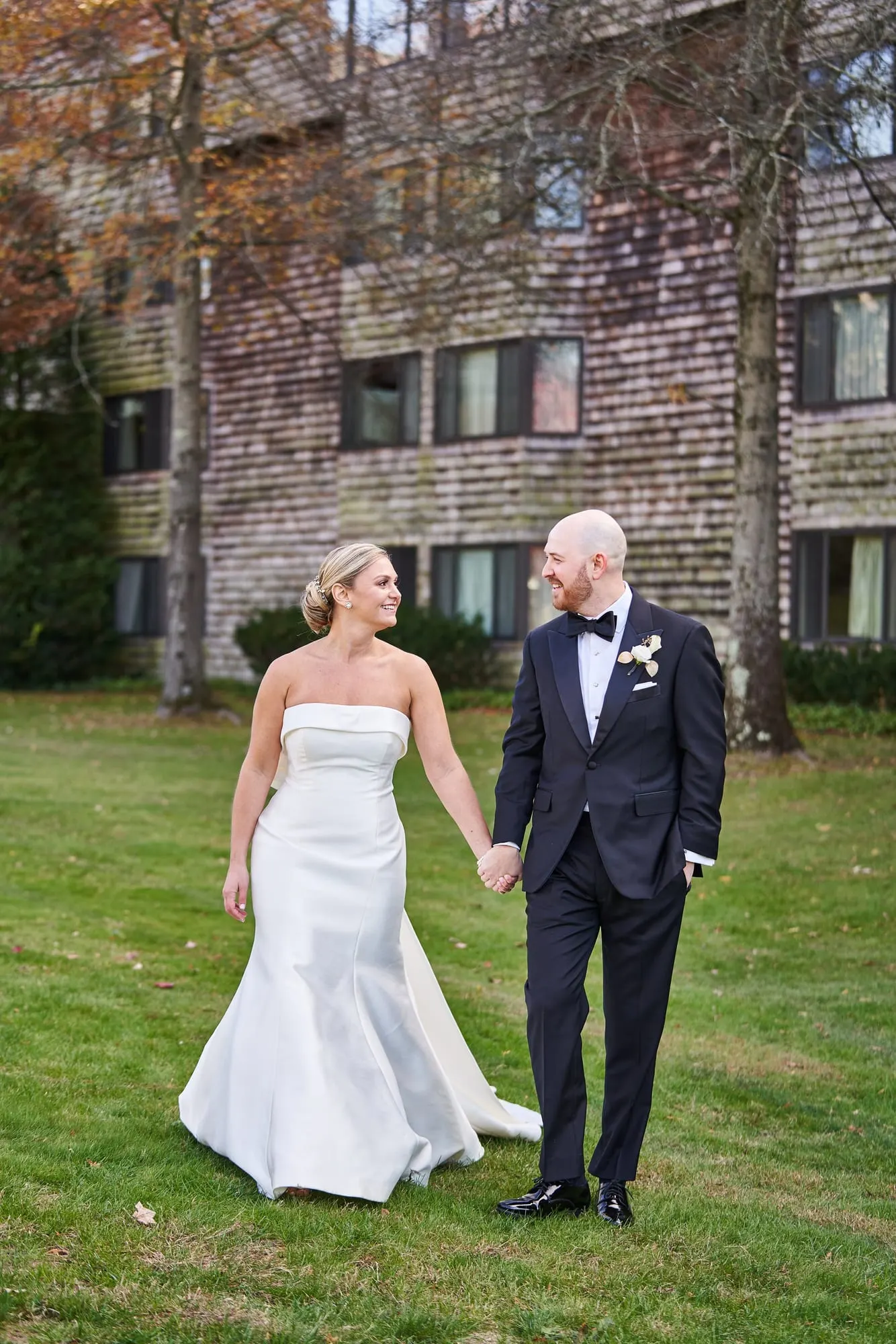 Bride and groom walking hand in hand across the grass