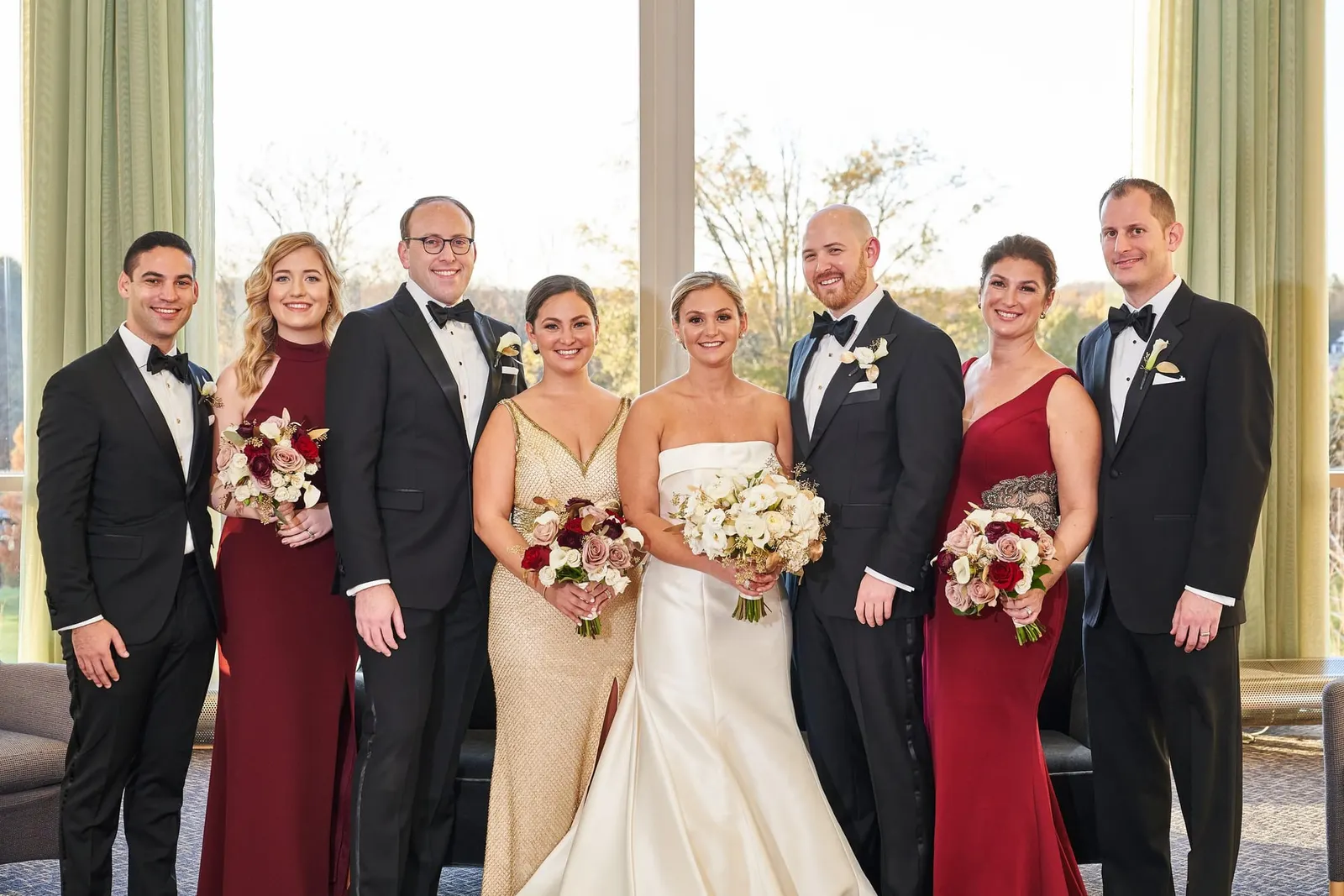 Bride and groom with bridesmaids in burgundy and gold gowns