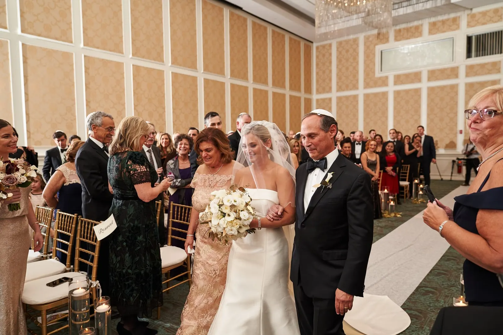 Guests watching as the bride is escorted down the aisle