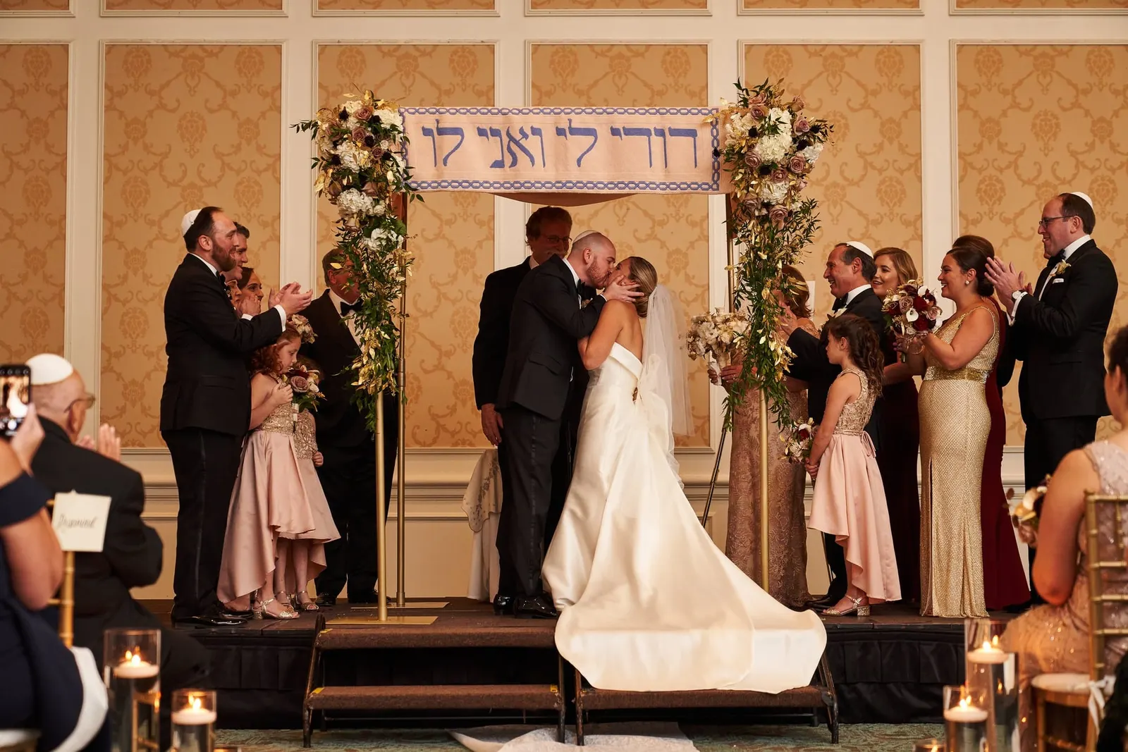 Bride and groom under the chuppah with their families gathered close