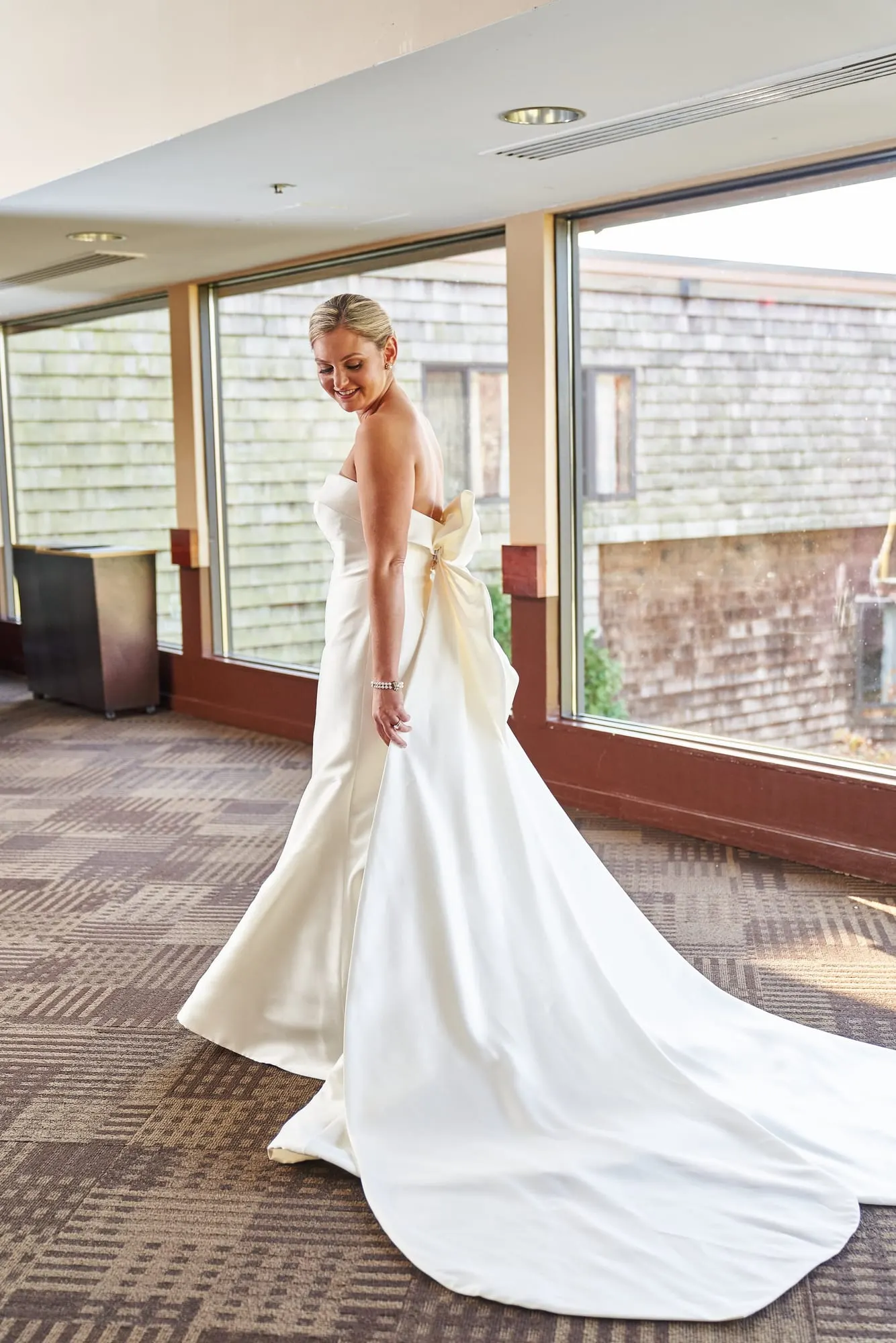 Bride in a strapless gown with a long train by the windows