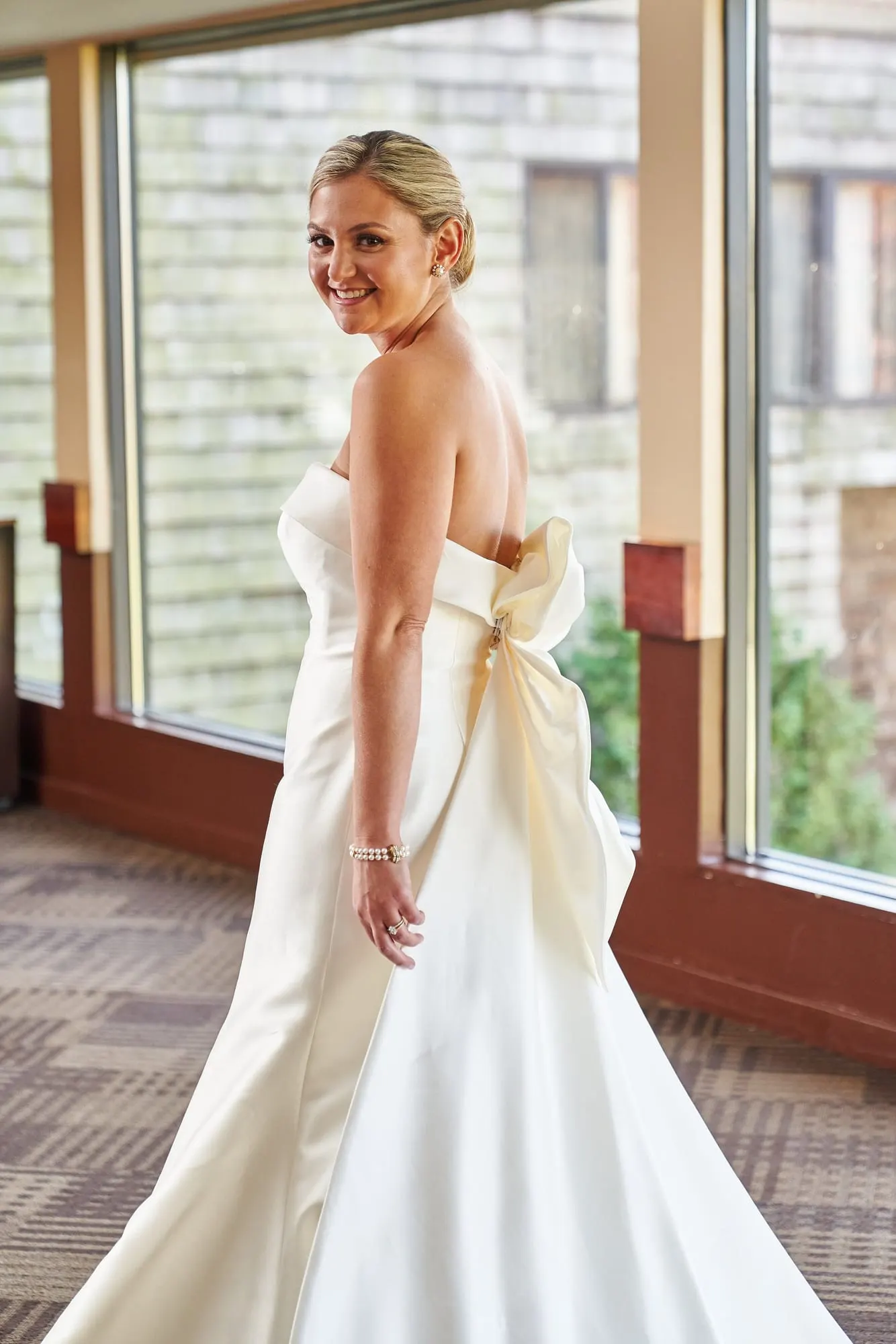 Bride looking over her shoulder to show the oversized bow on her gown