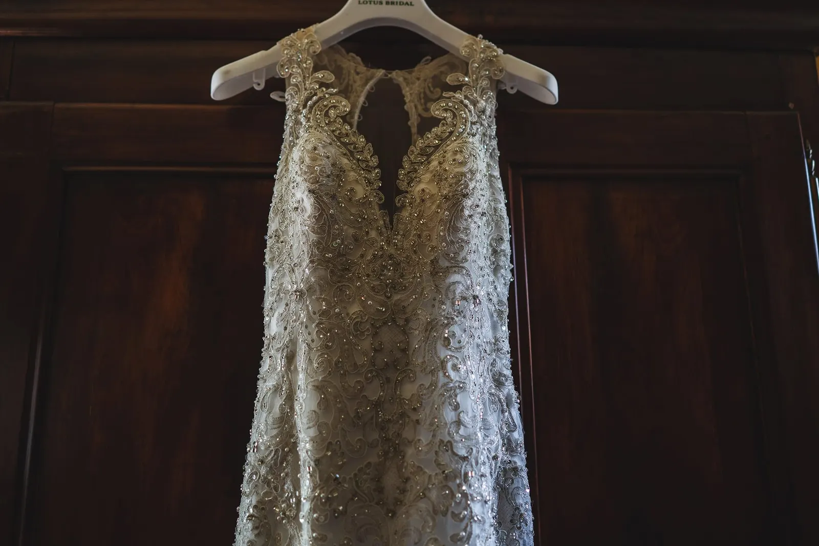 Lace wedding gown hanging in a sunlit room before the ceremony