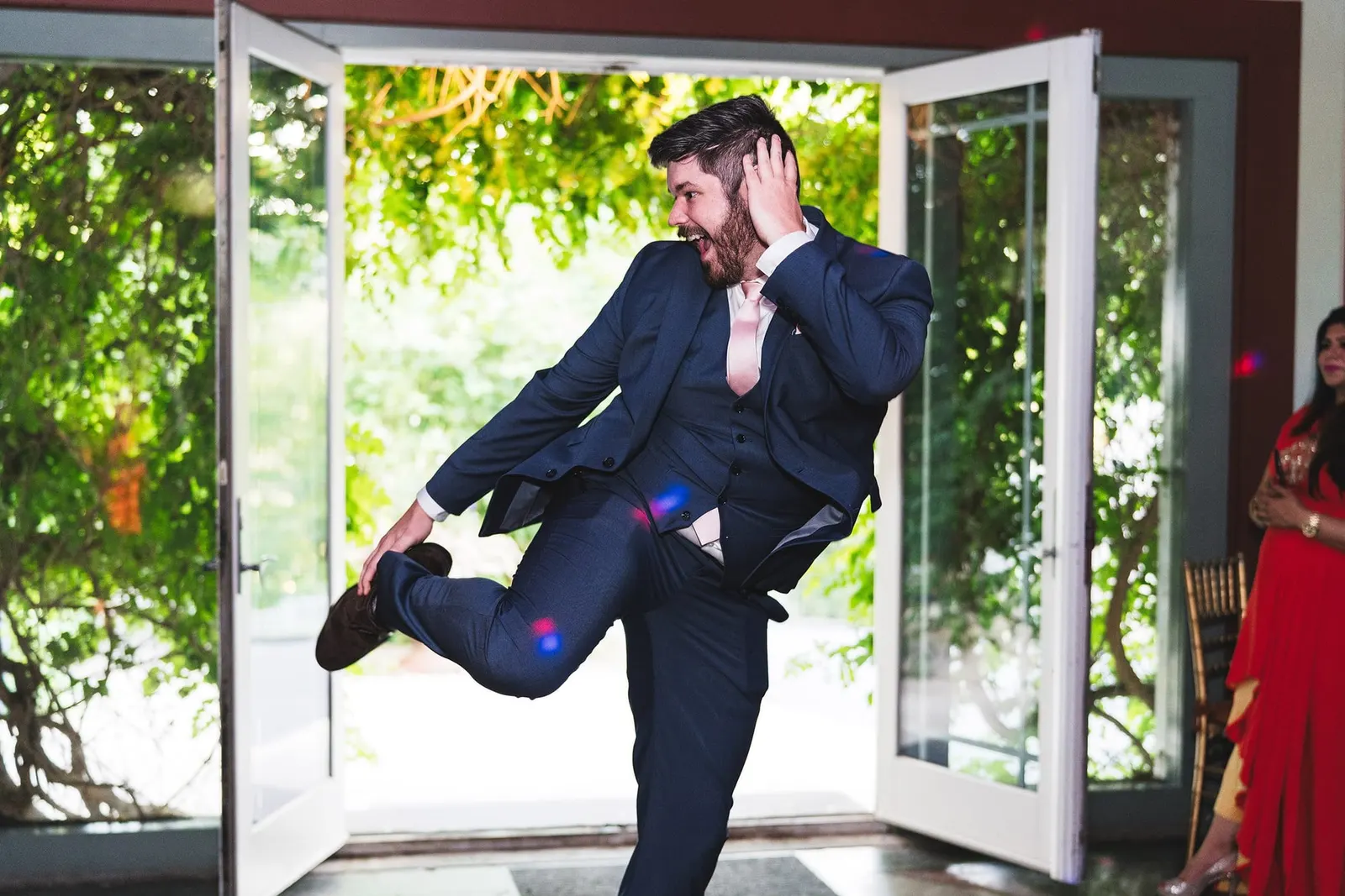 Groom making a joyful mid-air grand entrance into the reception